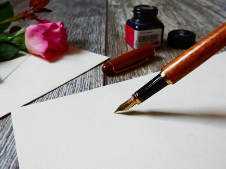 A romantic setup with a rose, fountain pen, and paper, perfect for heartfelt writing.
